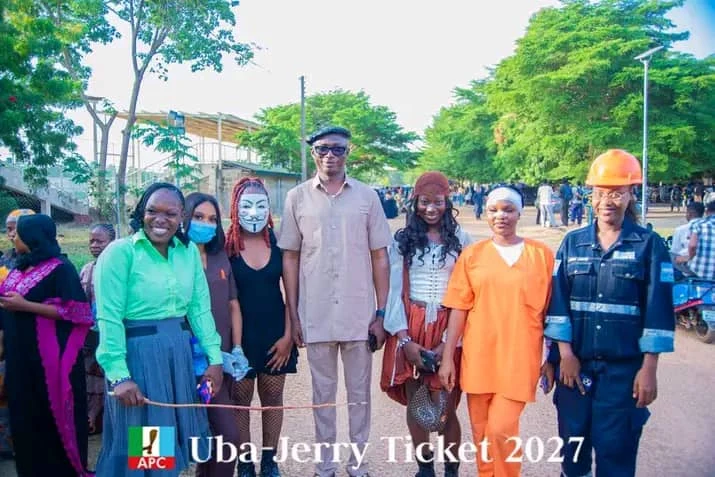 Jerry Adams with young people in colourful costumes at an outdoor gathering.