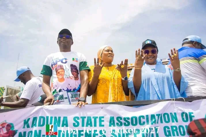 Jerry Adams beside supporters behind a Kaduna State Association of Non-Indigenes Support Group banner.